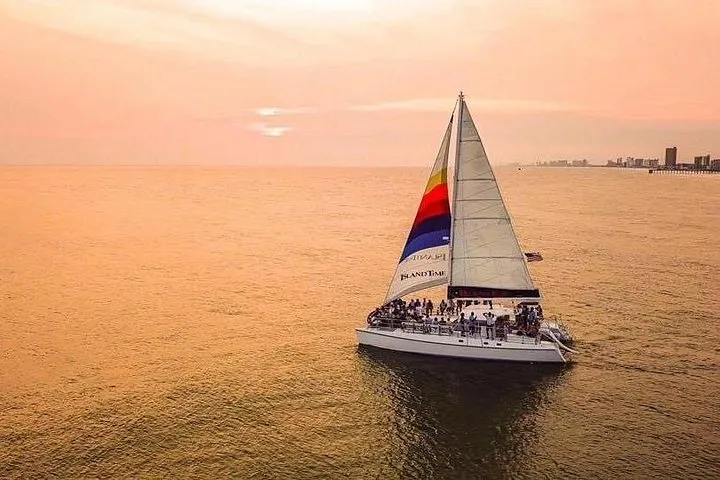 A catamaran under sail at sunset on a Shell Island dolphin tour at sunset from Panama City Beach, Florida
