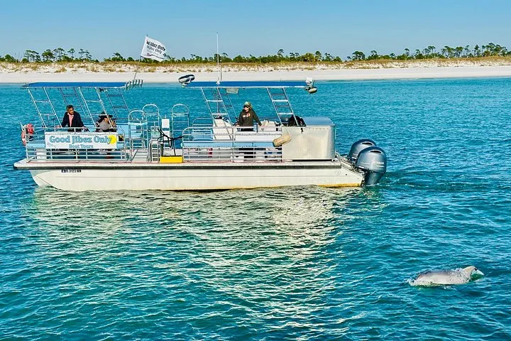 A white pontoon boat with guests on the water on a Shell Island dolphin tour from Panama City Beach, Florida