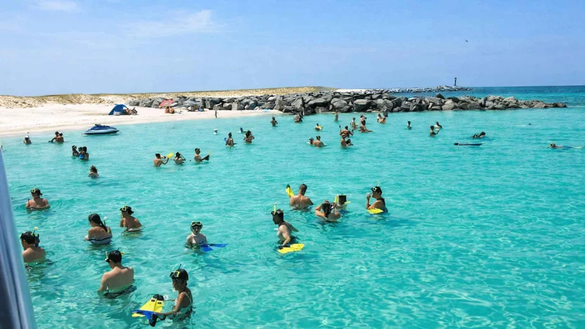 A cruise boat anchored beside the white sand beach of Shell Island on a Shell Island dolphin tour from Panama City Beach, Florida