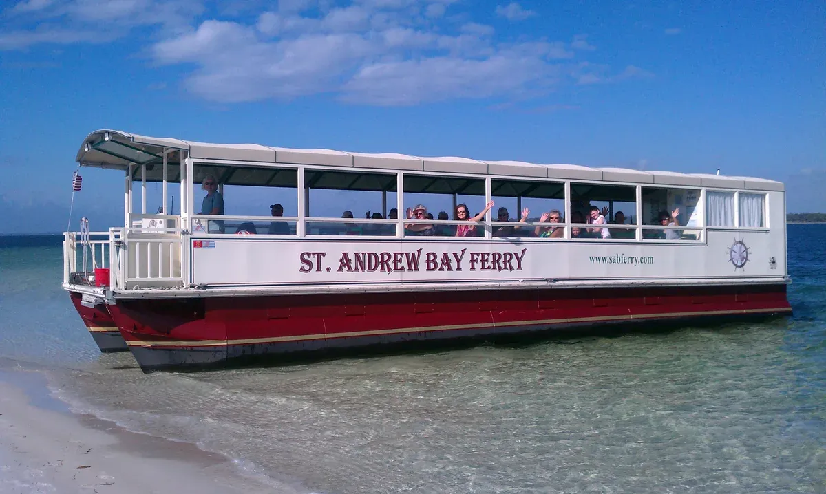 A passenger ferry landed nose-in on the sand of Shell Island with riders aboard, how boats drop visitors on Shell Island dolphin tour days near Panama City Beach